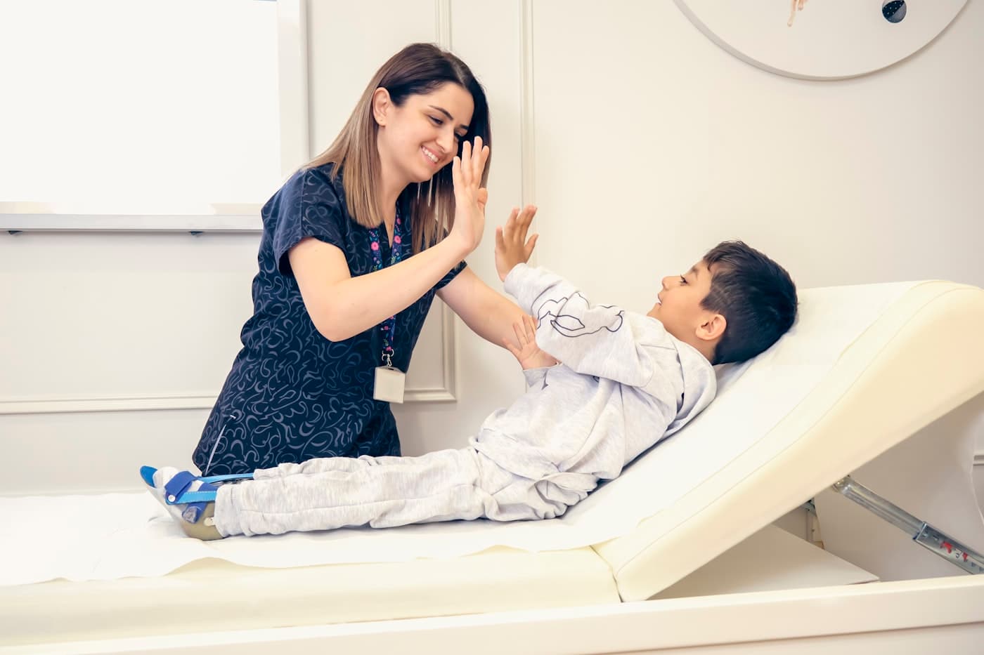 A pediatrician high-fiving a delighted young patient on the exam table